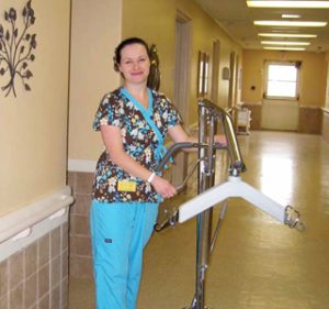 Woman nurse rolling equipment down a hallway